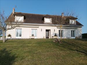 uma grande casa branca com um jardim de relva em Maison de campagne avec piscine em Le Blanc