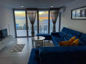 ein Wohnzimmer mit einem blauen Sofa und einem Tisch in der Unterkunft Sunny Coast Apartments in Sarandë