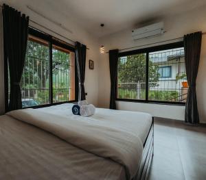 a bedroom with a large bed with two large windows at BREEZE THE HILLS in Trimbak
