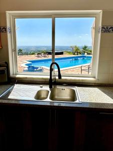 eine Küchenspüle mit Poolblick in der Unterkunft Fantastic villa with panoramic coastal & sea views in Estói