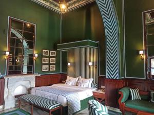 ein Schlafzimmer mit einem Bett und grünen Wänden in der Unterkunft The Jaipur House in Mount Ābu