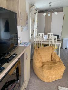 a living room with a television and a chair at Bude 13 in Cubert