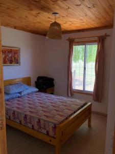 1 dormitorio con cama de madera y ventana en Casa Portal del Lago en El Mollar