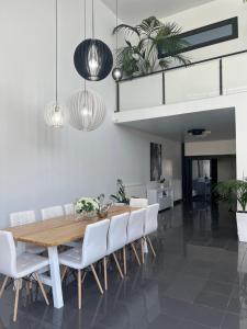 a dining room with a wooden table and white chairs at Two Bedroom Villa with Private Pool & Garden by Olivujoj in Anavyssos