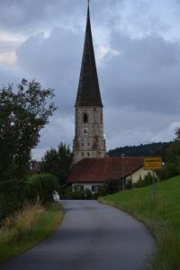 un campanario de la iglesia con una torre del reloj en una carretera en Zum Gänseglück, en Reut