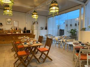 a restaurant with wooden tables and chairs and a kitchen at Calmaria Guesthouse in Porto Covo