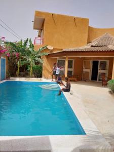 two people sitting on the edge of a swimming pool at La Georgeanne in Mbour