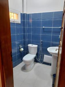 a blue tiled bathroom with a toilet and a sink at La Georgeanne in Mbour