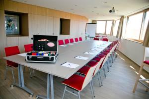 una gran sala de conferencias con una mesa larga y sillas rojas en Hotel Schönblick en Lochau