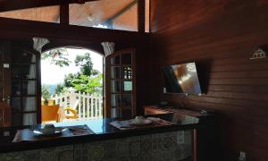 uma sala de estar com televisão e janela em Refúgio Hangarana em Angra dos Reis