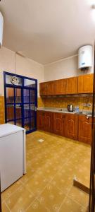 a kitchen with wooden cabinets and a white refrigerator at AL AMAN HOTEL in Al Buraymī