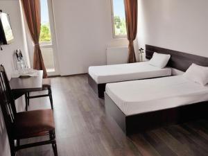 a room with two beds and a table and a desk at Hotel Grand in Nizhnyaya Alekseyevka