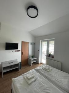 a white bedroom with a bed and a tv at HOTEL ZELENÝ DVOR in Senec