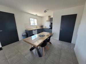 cocina con mesa de madera y sillas en Landes, maison de vacance jumelée à linxe, en Linxe