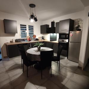 a kitchen with a table with chairs and a refrigerator at La villa de la Rivière du mât in Saint-André