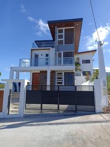 a large white house with a black fence at Casa Amores: Camaya Coast in Mariveles