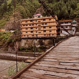 uma ponte sobre um rio com um edifício sobre ele em Ahsania Hotel & Restaurant em Bālākot