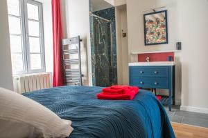 - un peignoir rouge assis sur un lit bleu dans une chambre dans l'établissement Les Jardins de l'Orangerie, à Durtal