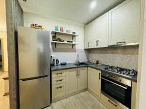 a kitchen with white cabinets and a stainless steel refrigerator at Tbilisi-apartment in Tbilisi City
