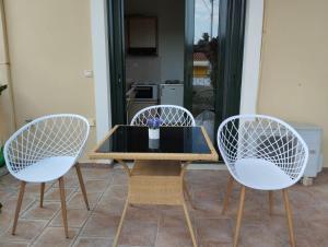 a table with three white chairs and a table with a vase at LEONIDAS in Káto Vasilikí