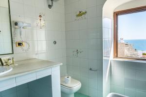 baño con aseo y lavabo y ventana en S. Martin Hotel, en Giovinazzo