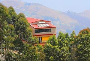 uma casa com um telhado vermelho no topo de uma colina em The Garudan Mountain View Residency em Kodaikanal