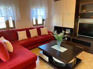 a living room with a red couch and a table at Guest House Persa in Gjirokastër