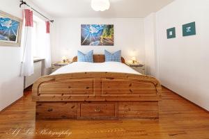 a bedroom with a large wooden bed with blue pillows at Pension Karner in Mittenwald