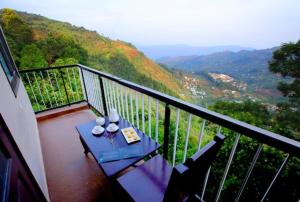 uma varanda com uma mesa com copos de vinho em The Garudan Mountain View Residency em Kodaikanal