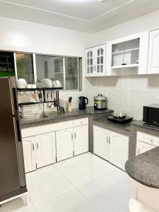 a kitchen with white cabinets and a black refrigerator at Explore Iloilo - Accessible Apartment in Iloilo City