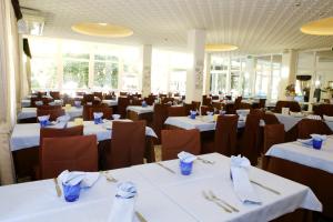 un comedor con mesas blancas y sillas marrones en Hotel Jolie, en Rímini