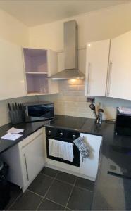 a kitchen with white cabinets and a black counter top at Modern Quiet City Center Airport 2 Bedroom Apartment in Edinburgh