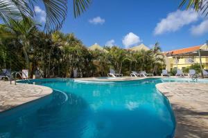 - une piscine dans un complexe avec des chaises et des palmiers dans l'établissement Bonaire Village Villa 23, à Kralendijk
