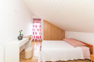 ein weißes Schlafzimmer mit einem Bett und einem Fenster in der Unterkunft Apartments Iskra in Split