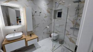 a white bathroom with a sink and a shower at Premier House by RD Group in Korenica