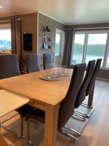 una mesa de madera con sillas y copas de vino. en Nice house with a great view! en Skjervøy