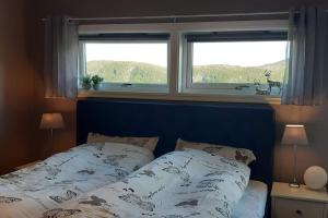 a bedroom with a blue bed with two windows at Nice house with a great view! in Skjervøy
