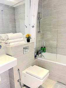 een badkamer met een toilet, een wastafel en een bad bij Harrow Apartments in Londen