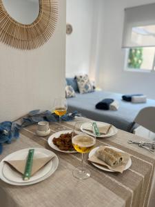 una mesa con dos platos de comida y copas de vino en Estudio coqueto con Terraza, en Alicante