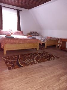a bedroom with two beds and a rug on the floor at La Marian pensiune restaurant in Munună