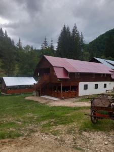 a large wooden barn with a red roof at La Marian pensiune restaurant in Munună