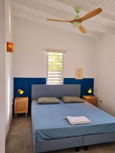 um quarto com uma cama azul e uma ventoinha de tecto em 12B Flamingo em Kralendijk