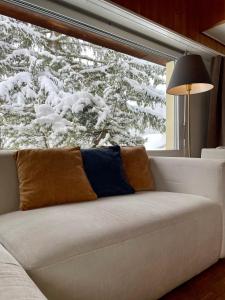 a white couch in front of a window with snow at The Holiday Home Davos in Davos