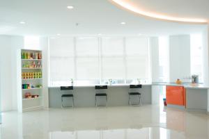 a white kitchen with a counter and stools at 1Orange Hotel Sri Petaling in Kuala Lumpur