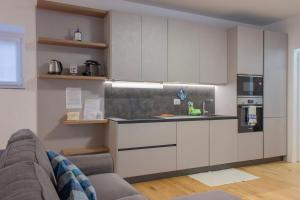 uma cozinha com armários brancos e um sofá num quarto em [Casa Ardo] Wifi & Free Parking in Lecco center em Lecco