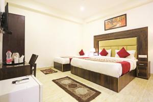 a hotel room with a large bed with red pillows at Kiara-By Aashiyana Group Near Delhi Airport in New Delhi