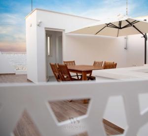 comedor con mesa, sillas y sombrilla en WHITE SOFIA - uno sguardo sul mare, en Bari