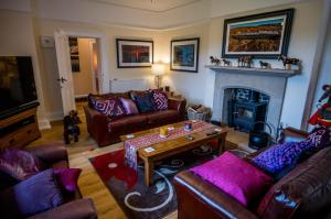 a living room with leather couches and a fireplace at Abbey Farmhouse 