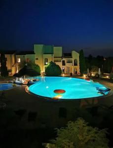 a large swimming pool in front of a house at night at Helena Stúdió Apartman in Siófok