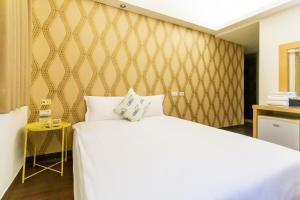 a bedroom with a white bed and a yellow wall at Newrise Hotel in Kaohsiung